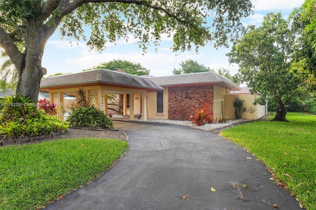 ranch-style home with fence, a carport, a front yard, and aphalt driveway