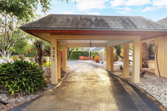 view of parking with driveway and a carport
