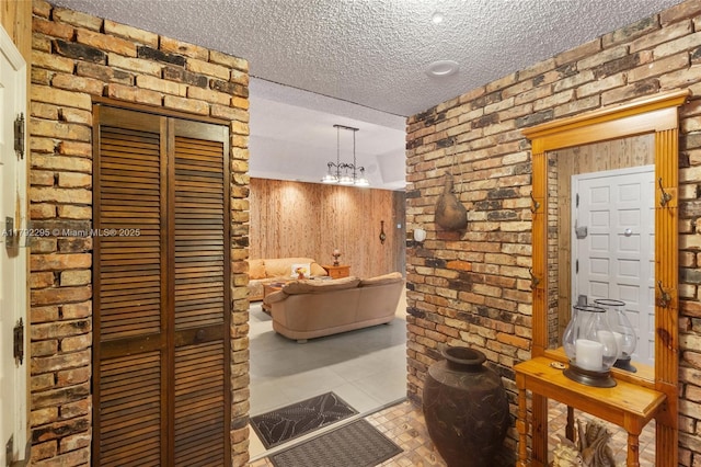 hallway featuring a textured ceiling, tile patterned floors, and brick wall