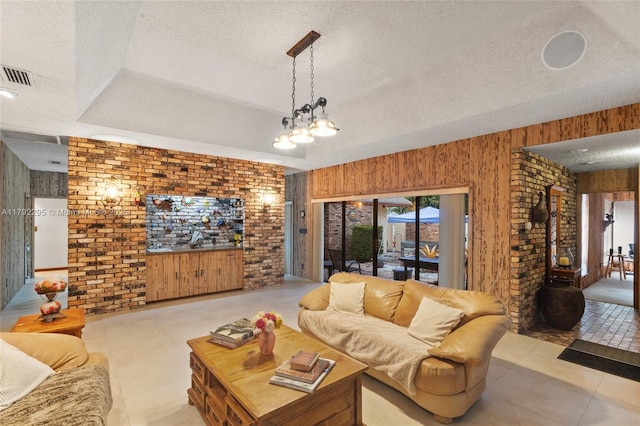 living room featuring brick wall, wood walls, a textured ceiling, and visible vents