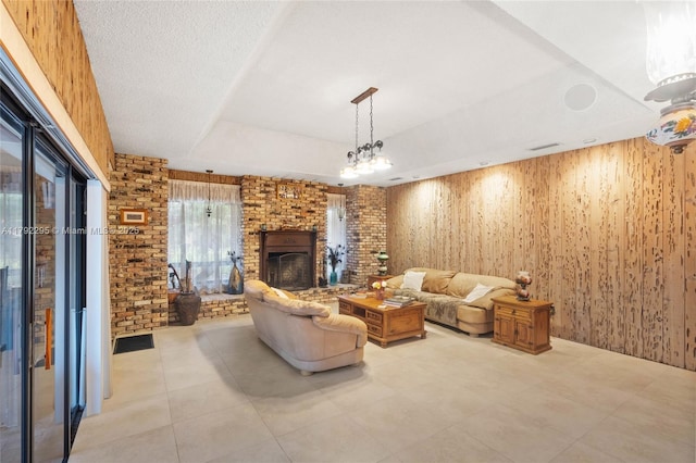 living room featuring wood walls, a raised ceiling, a brick fireplace, and light tile patterned floors