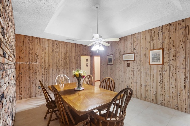 dining space featuring wooden walls and a ceiling fan