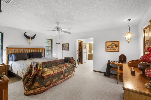 carpeted bedroom with a textured ceiling, ceiling fan, and ensuite bath