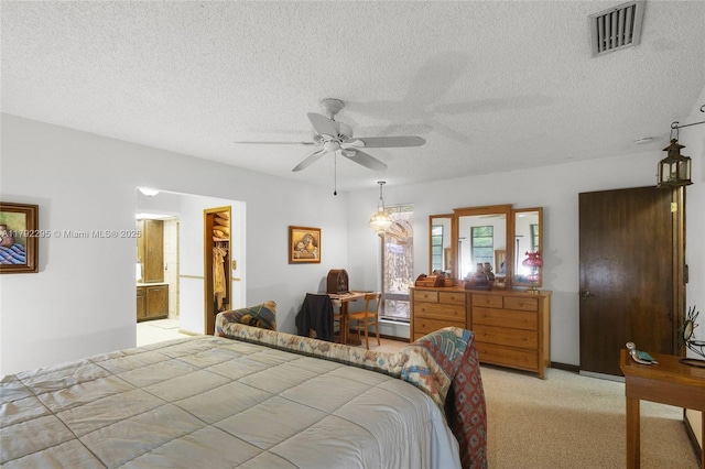 bedroom with a ceiling fan, a textured ceiling, visible vents, and light carpet