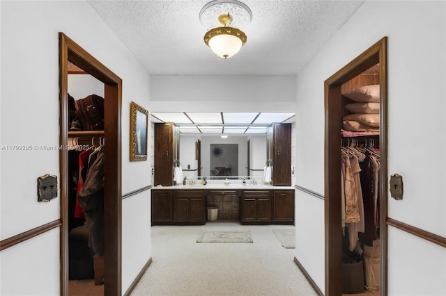 full bathroom with double vanity, a textured ceiling, and a walk in closet