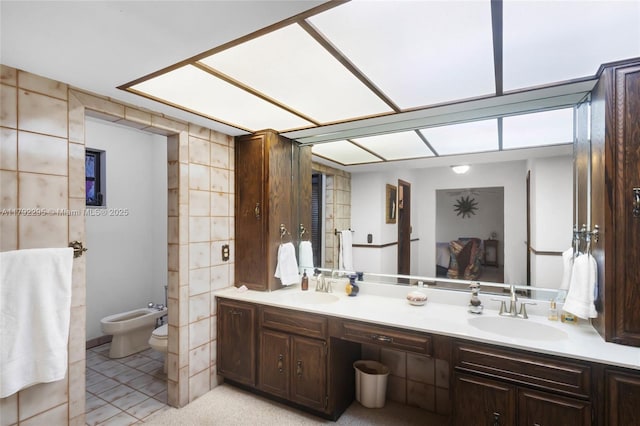 full bath with a sink, toilet, a bidet, and double vanity