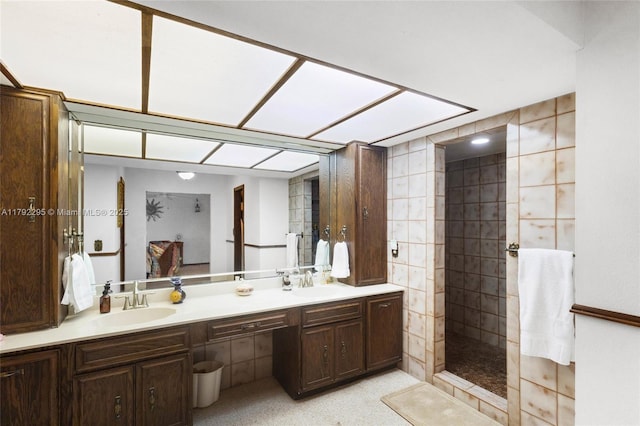 bathroom with double vanity, a sink, and tiled shower