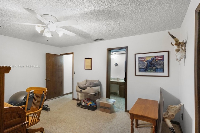 living area featuring carpet floors, ceiling fan, a textured ceiling, and visible vents