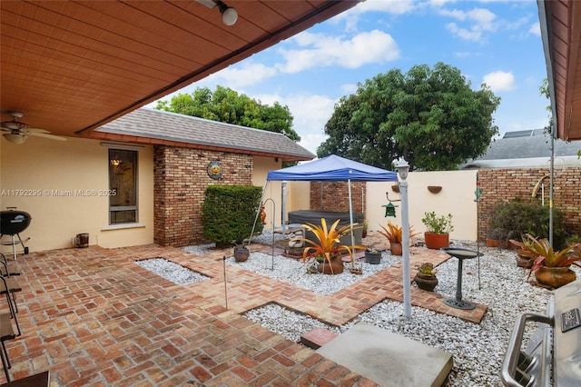 view of patio featuring a fenced backyard, ceiling fan, and a hot tub