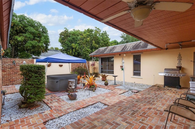 view of patio / terrace with a hot tub, ceiling fan, a fenced backyard, and a grill