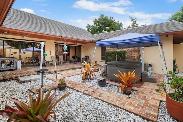 rear view of house featuring a hot tub, a patio, a gazebo, and a shingled roof