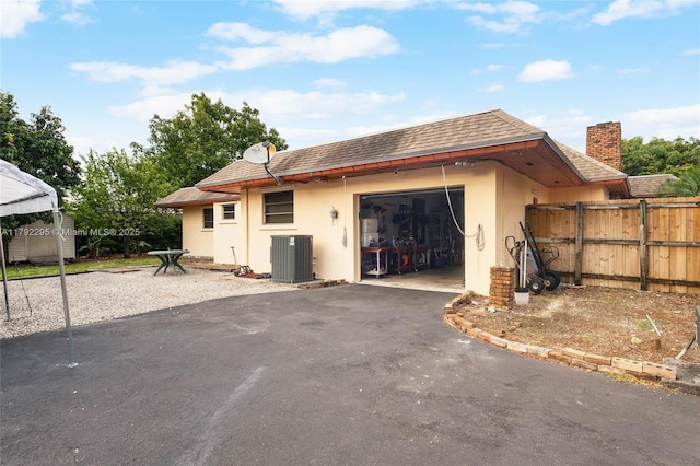 garage featuring central air condition unit, driveway, and fence