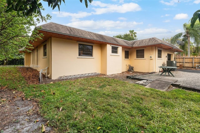 back of property with fence, central AC, stucco siding, a patio, and a yard