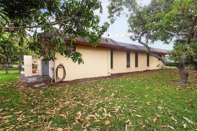view of home's exterior with a lawn, fence, and stucco siding