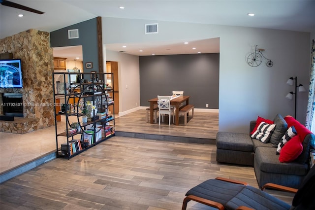 living room featuring a fireplace, lofted ceiling, wood finished floors, and visible vents