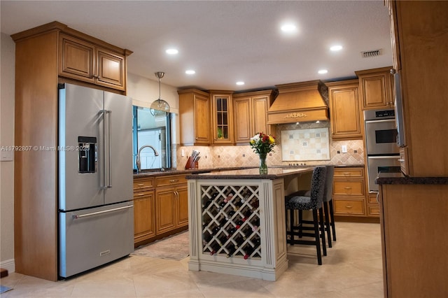 kitchen featuring visible vents, custom exhaust hood, brown cabinets, backsplash, and stainless steel appliances