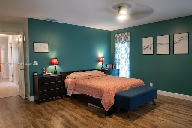 bedroom with visible vents, a ceiling fan, baseboards, and wood finished floors