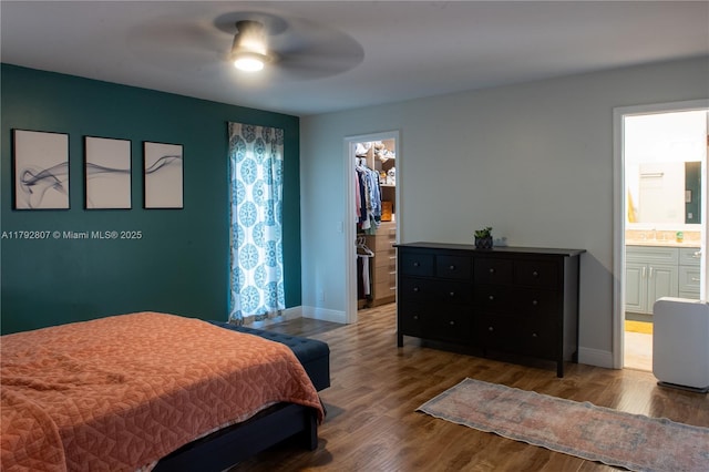 bedroom featuring connected bathroom, baseboards, wood finished floors, a spacious closet, and a closet