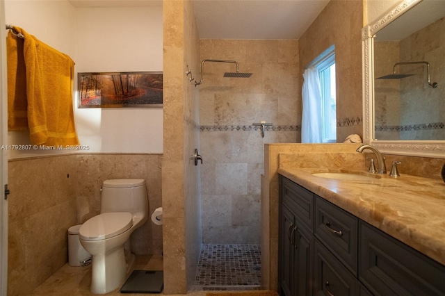 full bath featuring vanity, a tile shower, toilet, and tile walls
