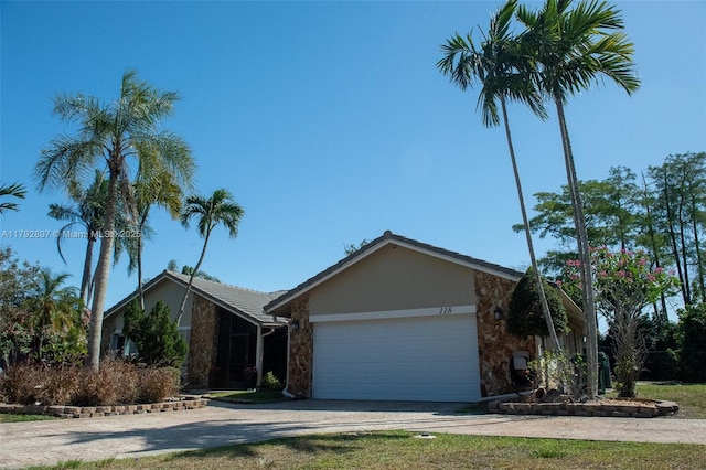 single story home with a garage, driveway, and stone siding