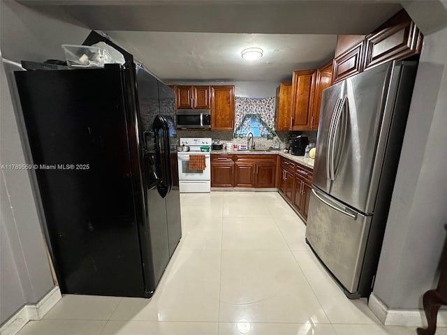kitchen featuring backsplash, light countertops, a sink, appliances with stainless steel finishes, and light tile patterned floors