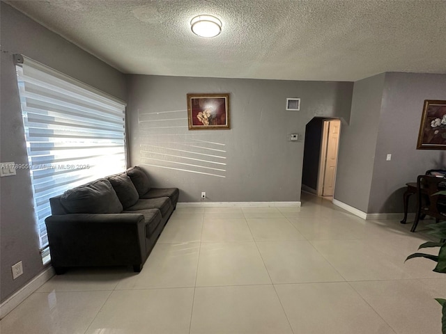 living room with light tile patterned floors, baseboards, a textured ceiling, and a wealth of natural light