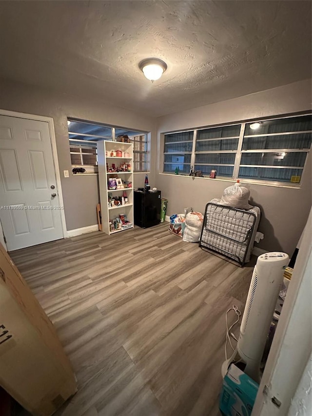 interior space with baseboards, a textured ceiling, and wood finished floors