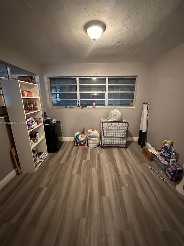 unfurnished room with baseboards, a textured ceiling, and wood finished floors