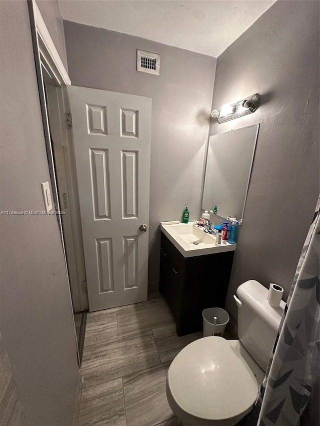 bathroom with vanity, toilet, and visible vents