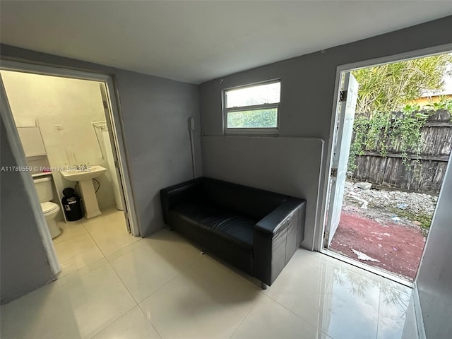 bedroom featuring light tile patterned floors, ensuite bath, and a sink