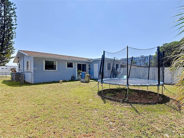 14320 NE 18th Ave, Miami, FL 33181 - rear view of house featuring a lawn, fence, a trampoline, and stucco siding