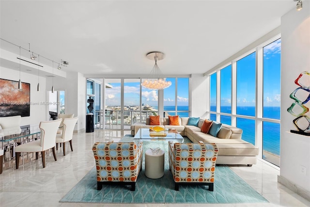 living area with an inviting chandelier, floor to ceiling windows, a water view, and track lighting