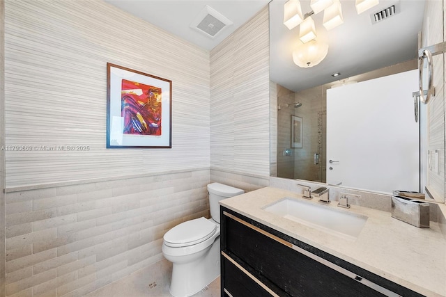 full bath with visible vents, tile walls, a stall shower, vanity, and toilet