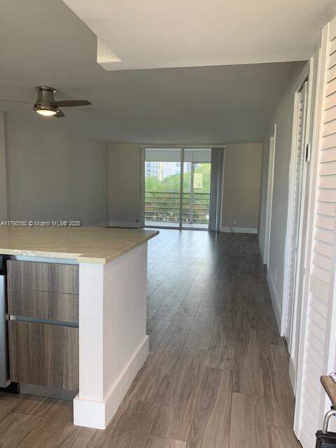 kitchen featuring wood finished floors, baseboards, open floor plan, modern cabinets, and ceiling fan