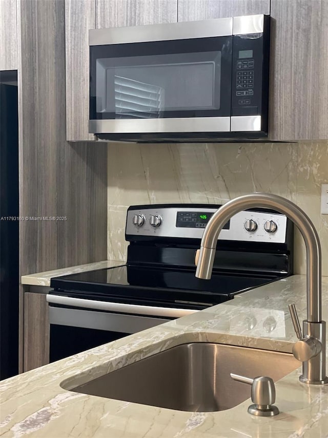 details featuring a sink, appliances with stainless steel finishes, and light stone countertops