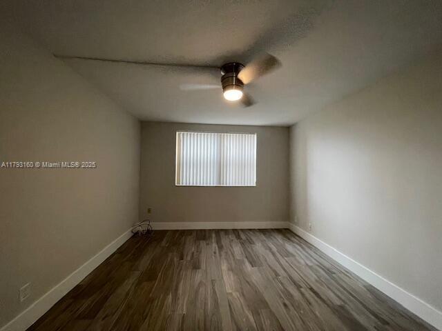 unfurnished room with baseboards, a ceiling fan, and wood finished floors