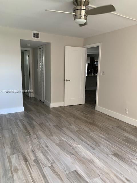 spare room with a ceiling fan, baseboards, visible vents, and wood finished floors