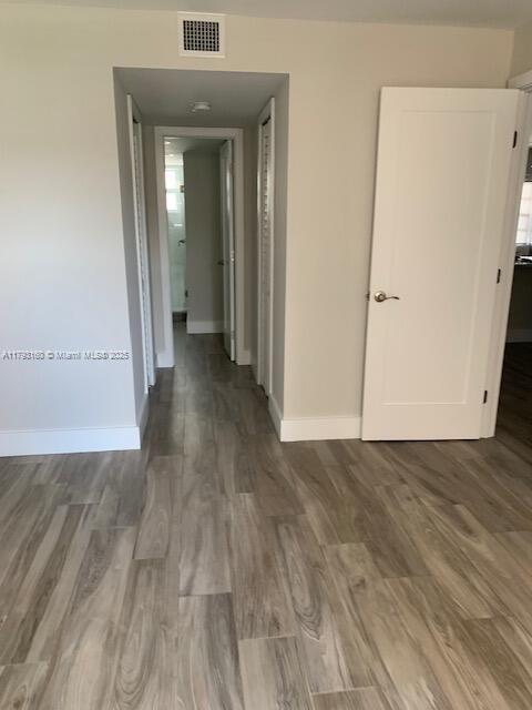 hall featuring baseboards, visible vents, and wood finished floors