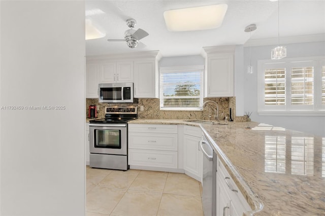kitchen featuring decorative backsplash, appliances with stainless steel finishes, a sink, light stone counters, and white cabinets