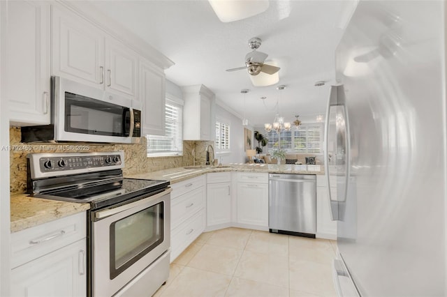 kitchen featuring light tile patterned flooring, ceiling fan with notable chandelier, stainless steel appliances, white cabinetry, and decorative backsplash