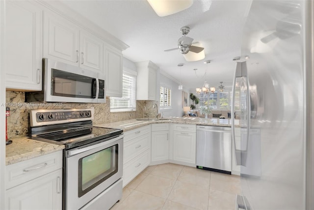 kitchen with ceiling fan with notable chandelier, light tile patterned floors, a sink, appliances with stainless steel finishes, and backsplash
