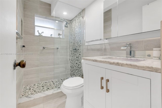 bathroom featuring vanity, tile walls, toilet, and a shower stall