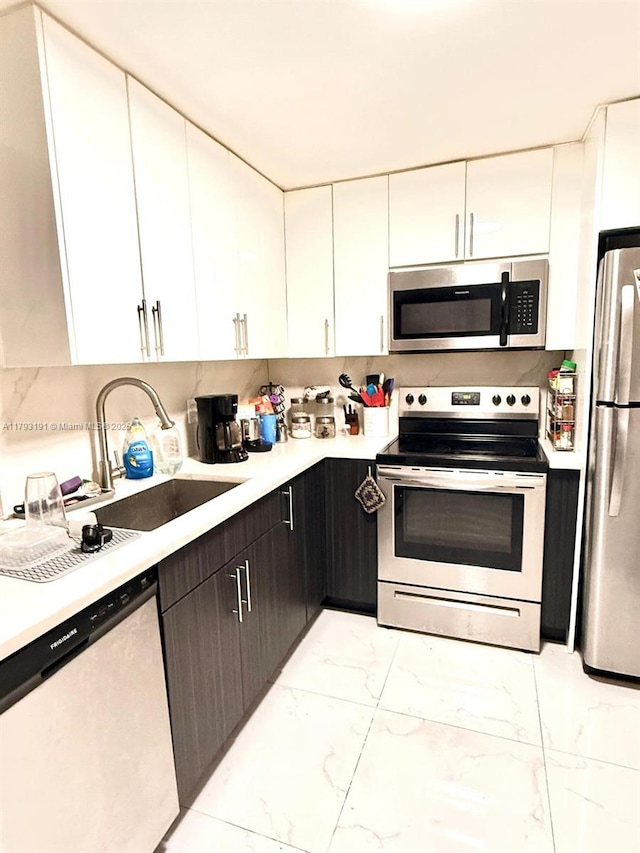 1401 NE 191st St Unit D201, Miami, FL 33179 - kitchen with light countertops, a sink, white cabinets, marble finish floor, and stainless steel appliances
