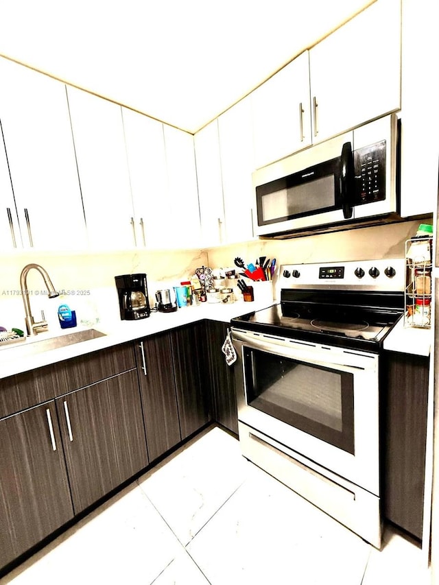 1401 NE 191st St Unit D201, Miami, FL 33179 - kitchen featuring dark brown cabinets, a sink, light countertops, white cabinets, and electric stove