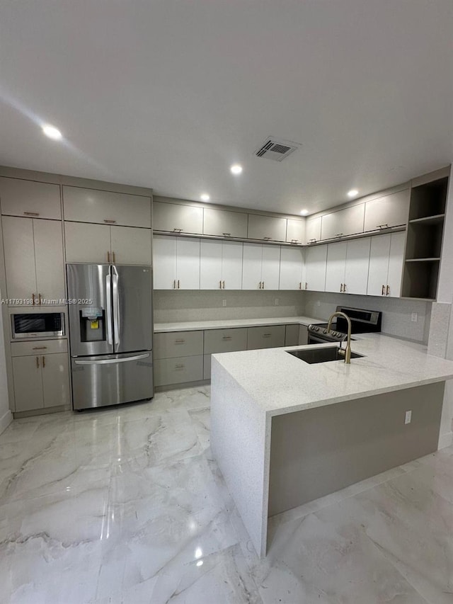 kitchen with visible vents, marble finish floor, a peninsula, a sink, and stainless steel appliances