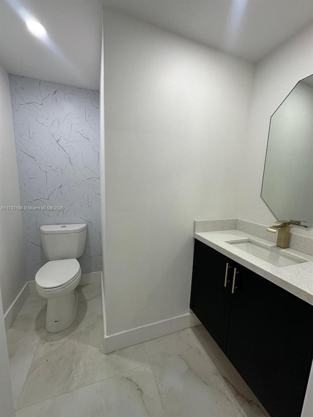bathroom with vanity, baseboards, toilet, and marble finish floor