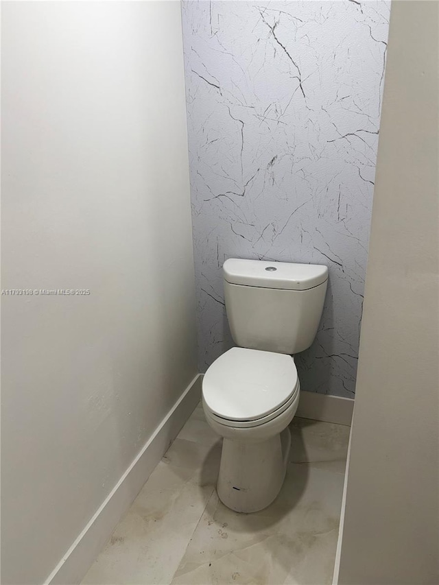 bathroom with baseboards, marble finish floor, and toilet