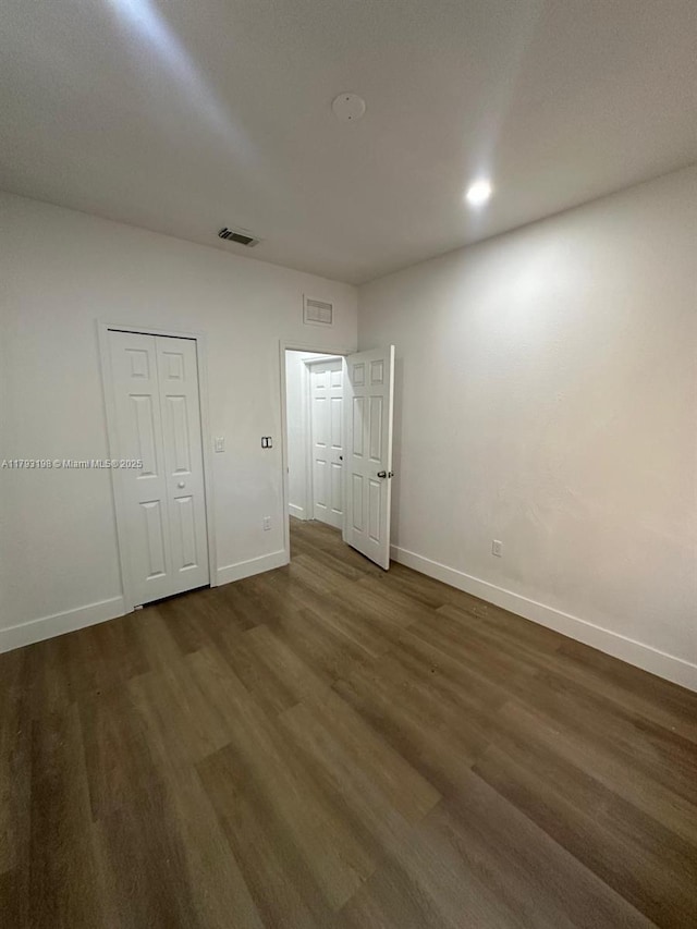 spare room with baseboards, visible vents, and dark wood-type flooring