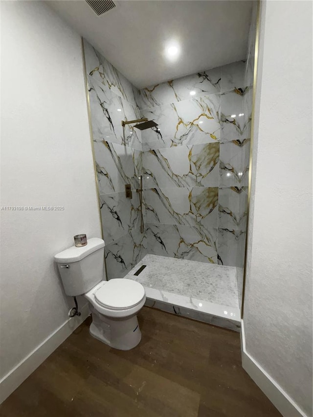 full bathroom with visible vents, wood finished floors, baseboards, toilet, and a marble finish shower