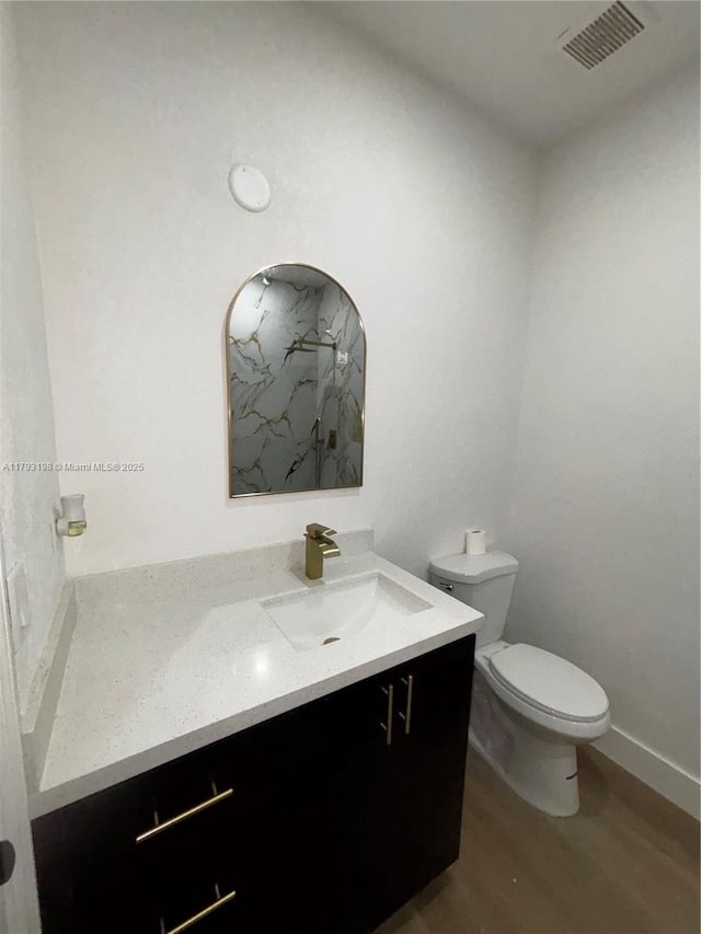 bathroom with visible vents, vanity, wood finished floors, toilet, and a marble finish shower